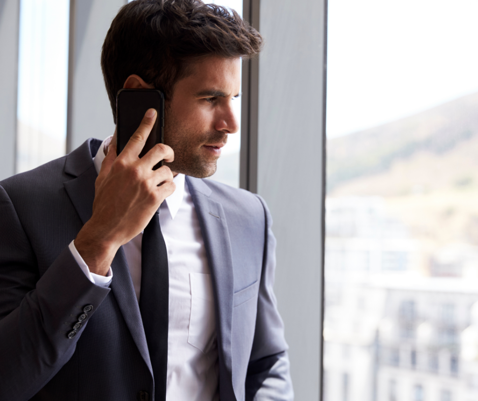 businessman making phone call standing by office window