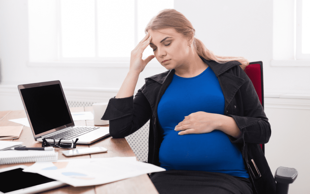 Tired pregnant businesswoman at office copy space