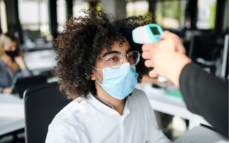 Young Man with Face Mask Back at Work in Office